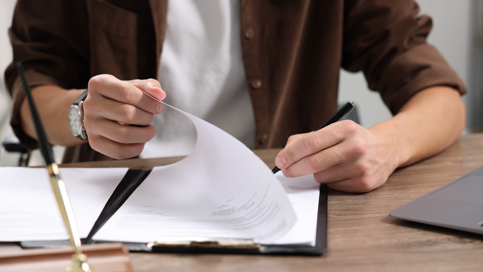 Person reviewing and signing legal documents at a desk, representing the personal representative paperwork needed to file a wrongful death claim in Oregon