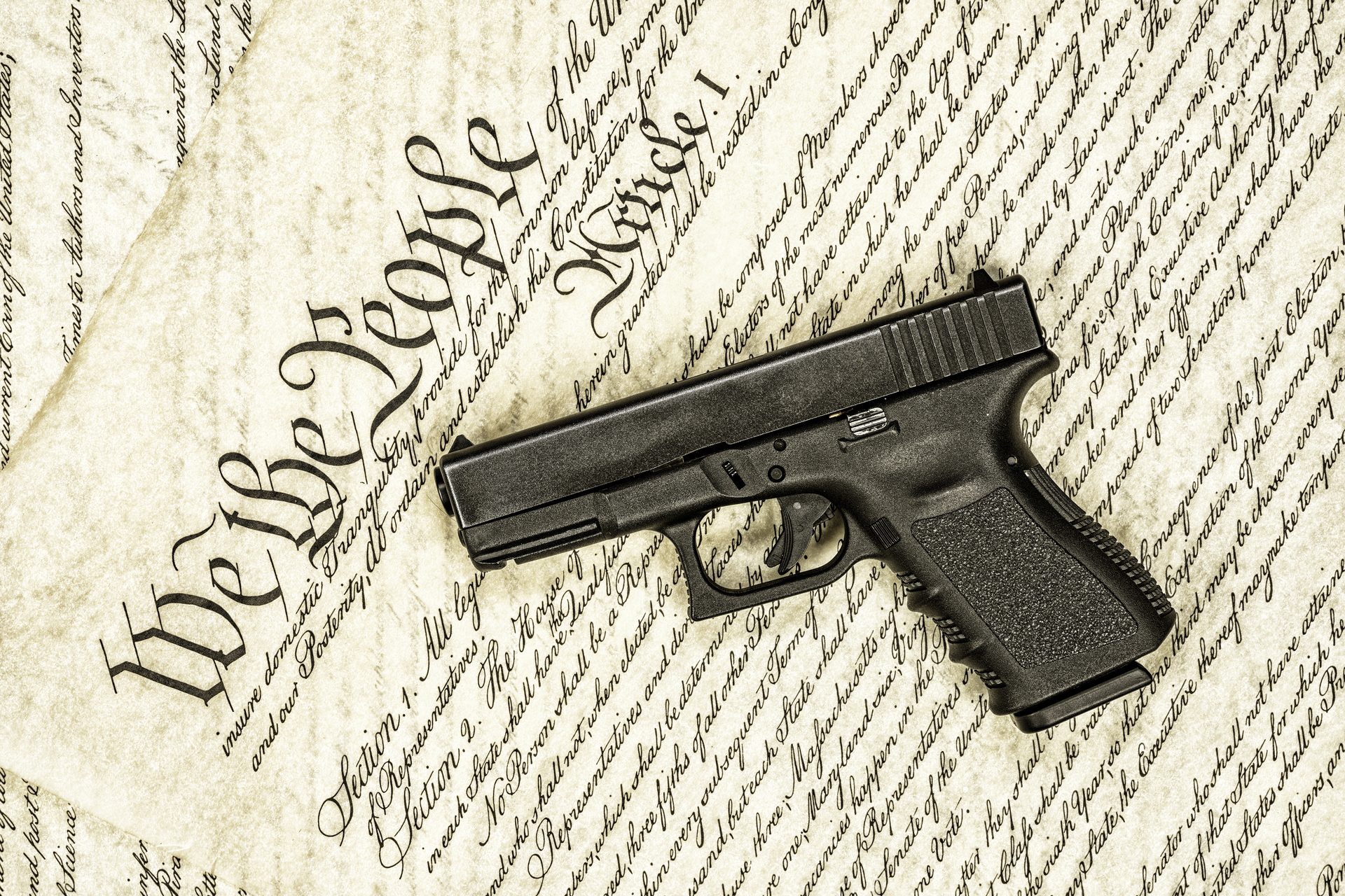 Handgun resting on a copy of the U.S. Constitution, representing the conflict between court-ordered Oregon firearm rights restoration and OSP background check denials